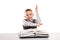 Child with books at desk gesturing hand up for answering school