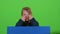 Child boy appeared from behind a blue poster grins curves of faces and hidden again. Green screen