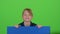 Child boy appeared from behind a blue poster to look at him hiding again. Green screen