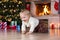Child boy crawling near Christmas tree in front of