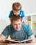 Child boy and father read a book on floor at home