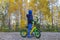 Child boy of five stands on the path in autumn forest holding behind the wheel cycling