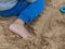Child boy foot playing on sand outdoor.