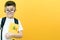 Child boy in glasses, on a yellow wall background. Great idea. Happy smiling schoolboy goes back to school. Success, motivation,