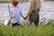 Child boy and grandfather going to fish together on riverside. summer vacation