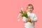 Child boy hold bouquet of flowers tulips. Studio shot on pink background with copy space