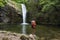 Child boy, little hiker with tourist backpack admiring falling stream of water of waterfall. Rhodope Mountains, Bulgaria