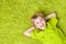 Child Boy lying on green carpet background. Smiling Kid