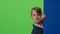 Child boy is over the board then appears and waves his hand in front on a green screen