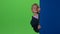 Child boy peeps out from the wall on a green screen