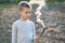 Child boy playing with smoking wooden stick outdoors