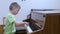 Child boy practicing playing piano in music lesson at musical class at school.