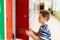 Child boy pulls out clothes from a metal school locker.