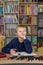 Child boy reads book from bookshelves in library. Bookstore concept, education and knowledge