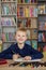 Child boy reads book from bookshelves in library. Bookstore concept, education and knowledge