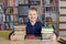 Child boy reads book from bookshelves in library. Bookstore concept, education and knowledge