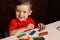 A child boy sculpts figures from multi-colored plasticine sitting at a table. Preschool education. Hobby. Self