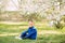 Child boy sits on sunlit glade in blooming garden