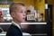 Child boy sitting in fast food restaurant behind empty table waiting for food