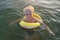 Child boy swims with yellow rubber ring. Sea travel with kid