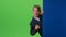 Child boy walks past a wall then appears and waving his hand on a green screen