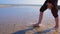 Child boy walks on shallow water in river flowing into the sea barefooted legs.