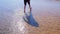 Child boy walks on shallow water in river with sand bottom barefooted legs.