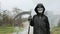 Child boy wearing in scary Halloween skull skeleton mask holding up a scythe in hand