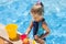 Child with bucket in swimming pool