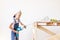 A child Builder holds a construction mixer against the background of a white wall and a construction ladder, a place for text, a