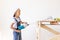 A child Builder holds a construction mixer against the background of a white wall and a construction ladder, a place for text, a