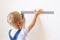 Child Builder measures a white wall with a construction ruler, space for text, construction and repair concept