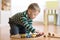 Child building and playing toy railroad at home or daycare. Toddler boy play with train and cars.