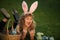 Child bunny boy with rabbit bunny ears. Child with easter eggs in basket outdoor. Boy laying on grass in park. Easter