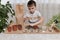 The child is busy planting seeds of micro greens in pots. Collects the earth in a fist from the table.