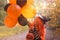 A child in a carnival costume on Halloween with large colored balloons. Little girl in the autumn park. The focus is