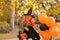 A child in a carnival costume on Halloween with large colored balloons. Little girl in the autumn park. The focus is