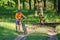 Child carries a bicycle through the forest