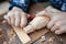 Child carves a toy in wood with a knife.  carpenter in the workshop. Close-up of hands.