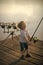 Child Childhood Children Happiness Concept. Child with fishing rod on wooden pier