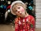 child in Christmas pajamas, Santa hat and a deer make-up painted on his face makes funny faces