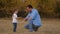 Child claps his father on the palm, a happy family is playing in the park. Dad and daughter greet. Joint work of the