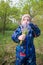 Child in a cold spring park holding little wild blue flowers