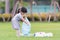 Child collect garbage on lawn. Asian girl puts plastic bottle in blue bag. Kid take care of environment.