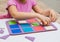 Child collects multicolored geometric shapes on a blackboard with squares