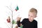 Child is concentration about decorating Metal wire Christmas tree, with glass Ornaments