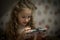 Child Concentration, Female Digital Native Looking Down Holding Technology. A concentrated female digital native looking down