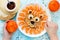 Child cooking and eating funny breakfast lion pancake with tangerines