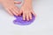 Child crumples slime. Close up of hands. Process of making slime.Purple magic glitter slime on a white background.