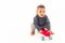 Child curiosity concept. Young multiracial baby boy playing with mini red skateboard in a studio over white background.